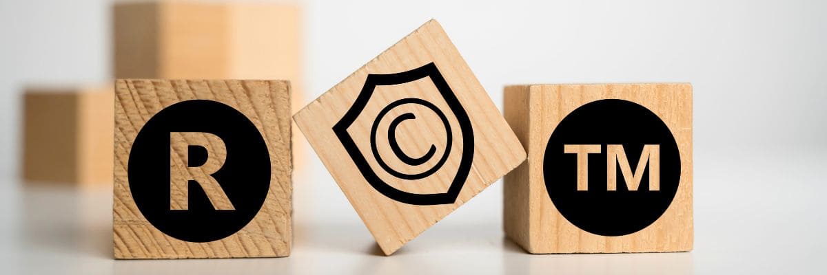 Protection, enforcement, and management of intellectual property rights, represented by 3 wooden blocks of IP symbols.